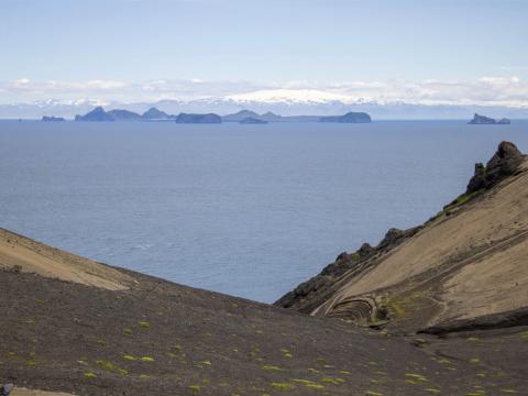 Frá Surtsey. Landsýn úr Svartagili til Vestmannaeyja á fögrum degi, í bakgrunni Tindfjöll og Eyjafjallajökull. Smágígurinn Strompur til hægri. 